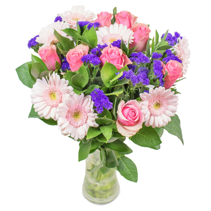 This strikingly vibrant bouquet, artistically composed by Enfield Florist, radiates with the harmonious energy of Enfield's lively community. Nestled in a clear glass vase with visible stems kept fresh in pure water, the bouquet features approximately seven to nine pink roses-some tightly furled, others just beginning to open, their timeless spiral shapes echoing traditional romance. Surrounding the roses, about five to seven pale pink gerbera daisies display their large, daisy-like faces and softer, almost white centres, their countless petals catching soft light reminiscent of a calm morning on Town Park's lawns. Clusters of brilliantly purple statice provide a punch of colour and textural contrast, calling to mind the vibrant wildflowers scattered through Enfield's meadows and gardens. Deep green foliage weaves throughout, offering an abundant and revitalising base that subtly scents the arrangement. The transparent vase enhances the bouquet's fresh, hand-tied look, perfect for a next-day delivery to Hadley Wood or as a thoughtful gift for birthdays, anniversaries, Mother's Day, or simply to brighten a room in a home off Enfield Chase. Every element has been selected for quality and local charm, honouring Enfield's welcoming spirit and the enduring beauty of its natural spaces.
